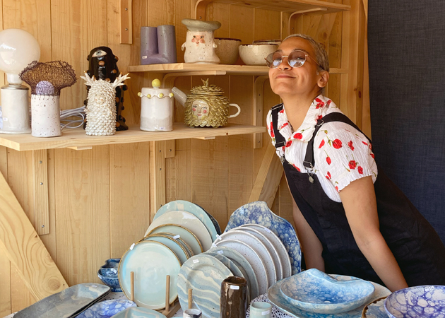 Eunice standing in a ceramic shop, surrounded by ceramic objects.