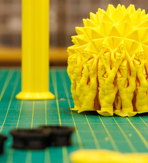 3D-printade föremål. Små svarat runda mutteraktiga dela och en gyl boll som är taggig.