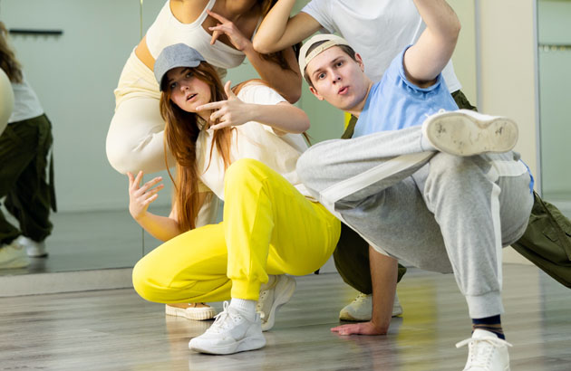 Team of positive teenagers rehearsing modern dances in dance hall